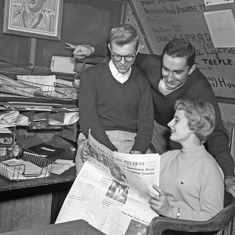 Three students read a paper at the Indiana Daily Student office in 1953.