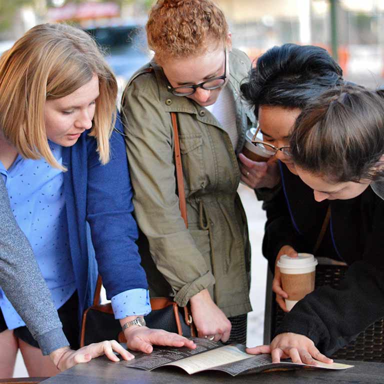 A group of students look at a brochure during a student trip.