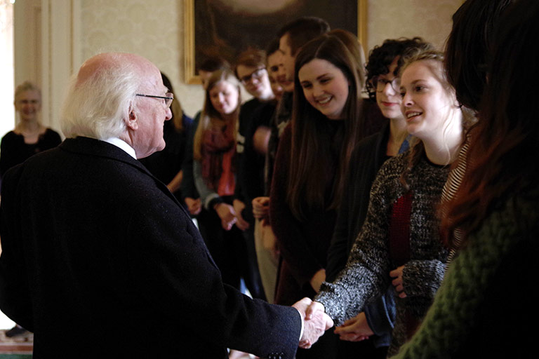 A group of students waits to meet and shake hands with a man in Ireland.