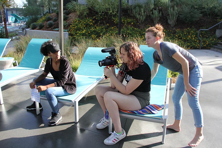 A group of students looks through a camera to plan out a shot.