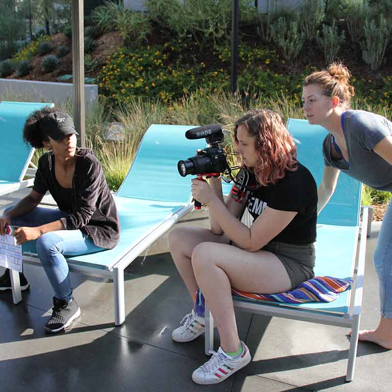 A group of women evaluate a shot through a camera.