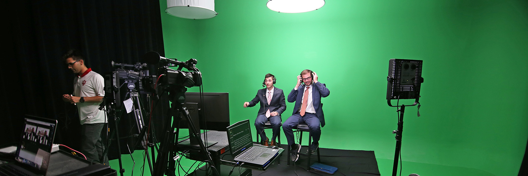 Students preparing to film in front of a green screen.