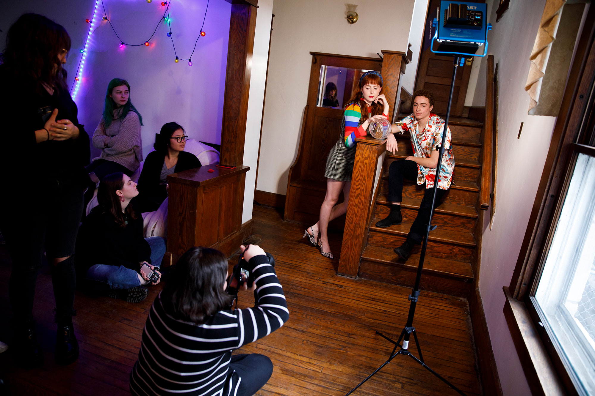 A fashion photo shoot in a house. The two models are on a staircase holding a hamster in a ball.