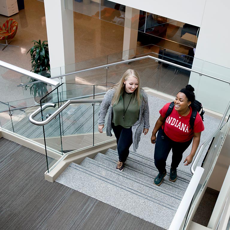 Two students walk up a stairway in the commons area of Franklin Hall.