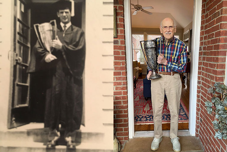 Two side-by-side photos. On the left, a black and white photo of Bernie Rosenthal standing in a doorway wearing a graduation cap and gown and holding a trophy. On the right, a current photo of Bernie Rosenthal standing in a doorway holding the same trophy.
