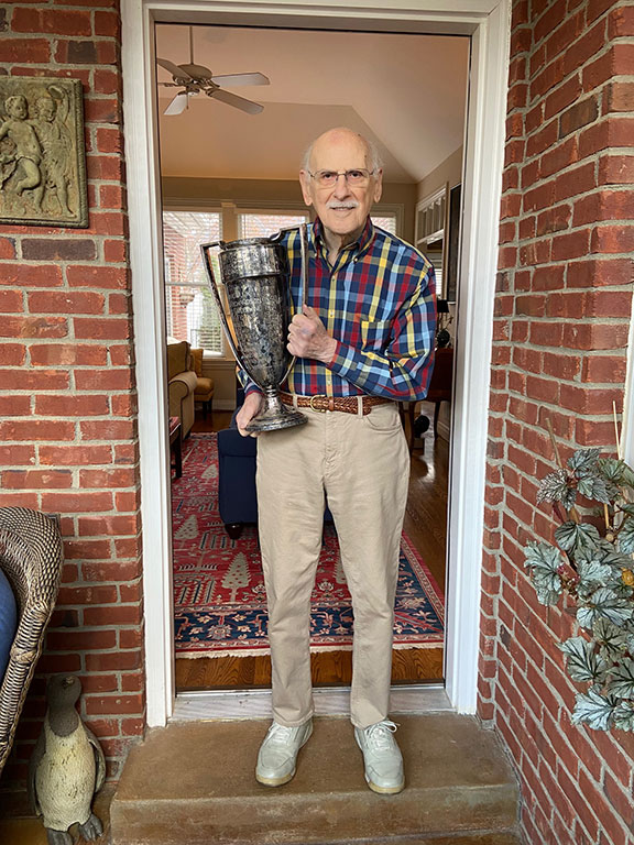 Bernie Rosenthal standing in a doorway holding a trophy.