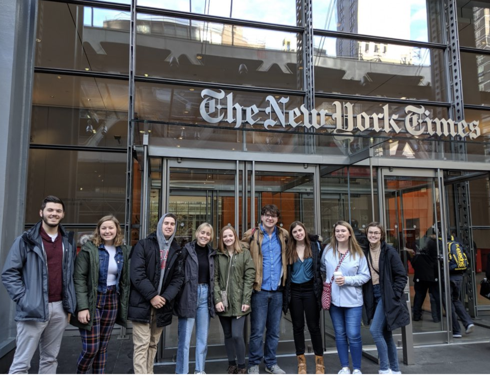 A group of students smile outside The New York Times building in New York City. 