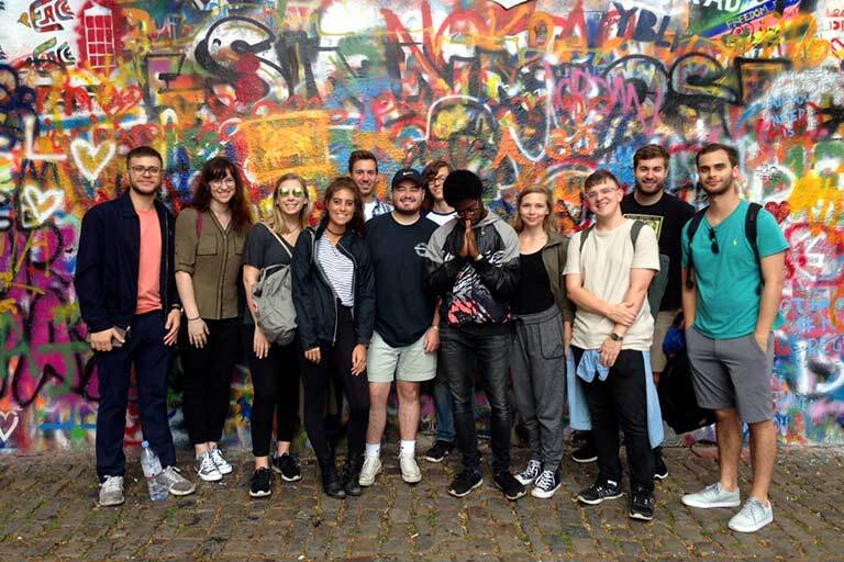 Students pose in front of the John Lennon Wall in Prague. Czech Republic.