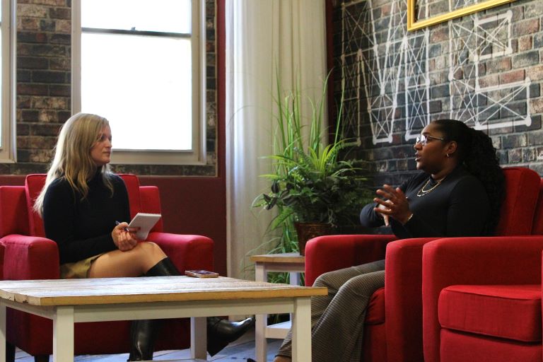 Two people are seated in a studio talking to one another.