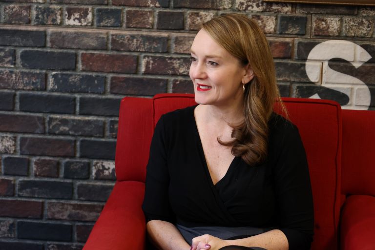 Person sits in a studio talking to someone off-camera.