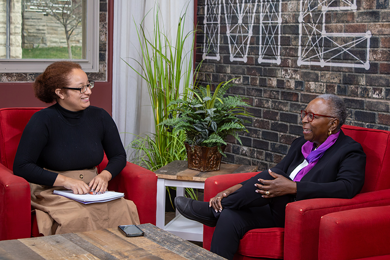 Lillian Dunlap speaks to an interviewer while sitting in chairs.