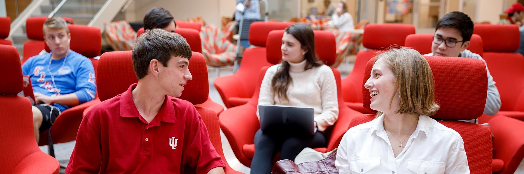 A group of students has a conversation in the Media School commons.