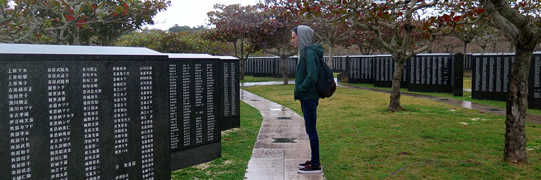 A student stands in front of a war memorial.