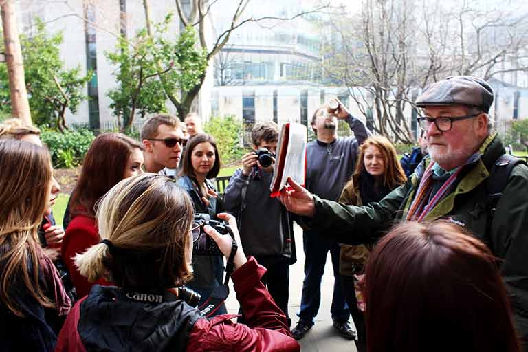 A group of people encircle a man and listen to him speak.